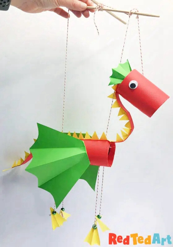 Child holding a colorful paper dragon puppet craft
