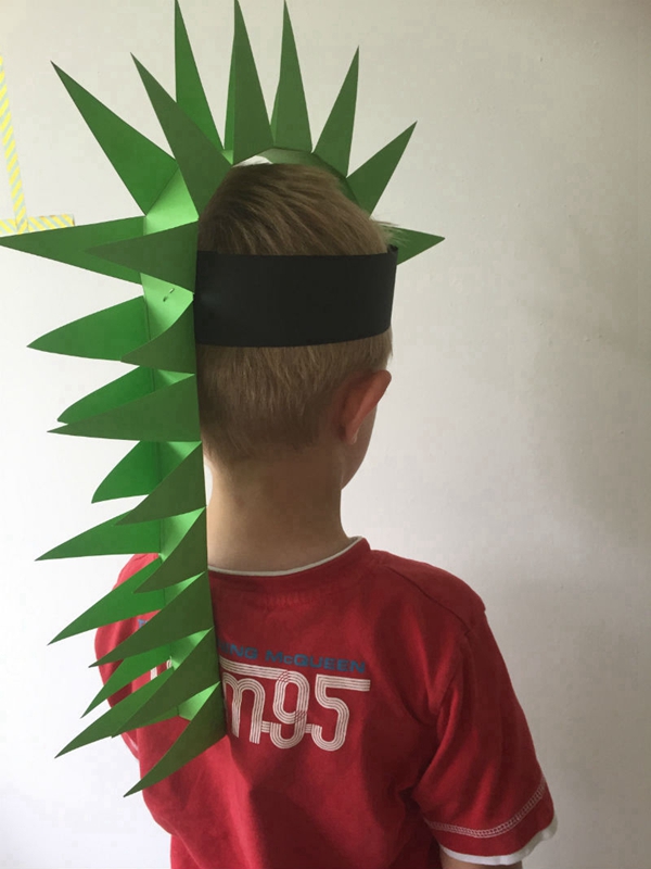 Child wearing a handmade dinosaur hat crafted from colored paper