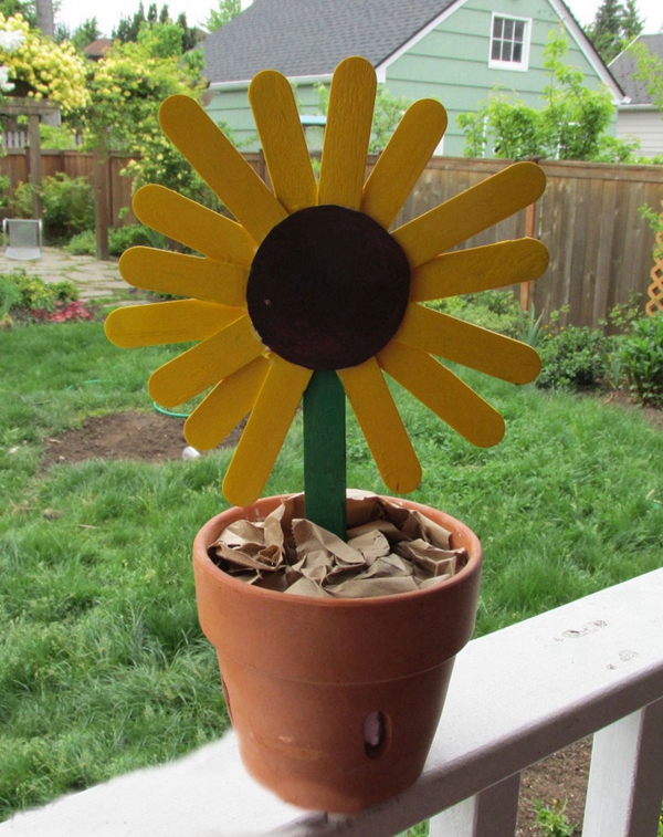 Handmade sunflower bouquet crafted from popsicle sticks, painted vibrantly, and placed in a decorative pot.