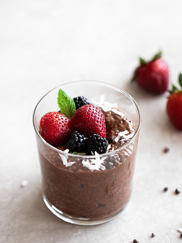 Glass of Chocolate Chia Pudding topped with fresh blackberries and strawberries.