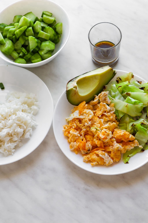 A bowl of Healthy Fried Rice Breakfast, featuring scrambled eggs, a variety of fresh vegetables, and a tasty tamari-sesame-wasabi sauce, providing a nutritious and savory breakfast option.