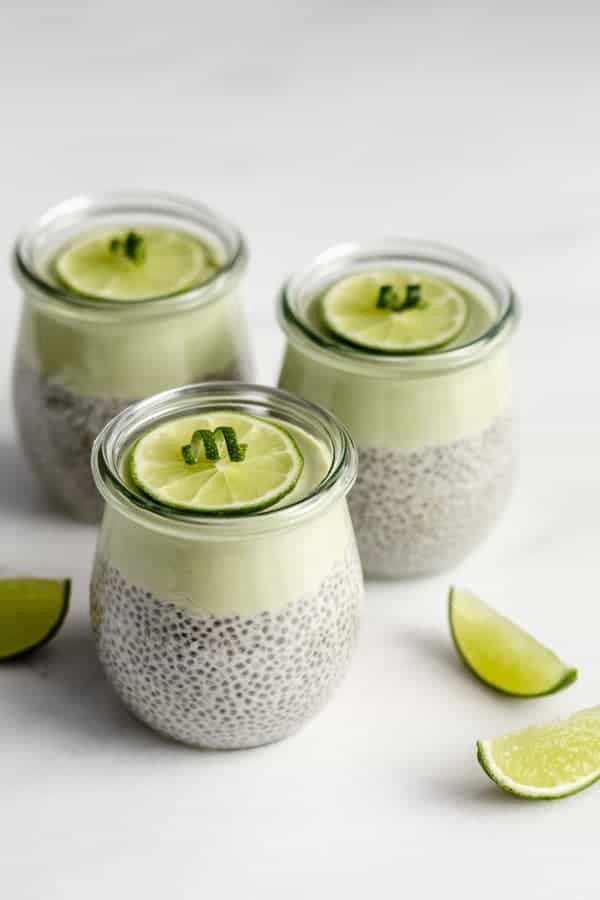 Three jars of Key Lime Pie Chia Pudding with lime wedges on the side.