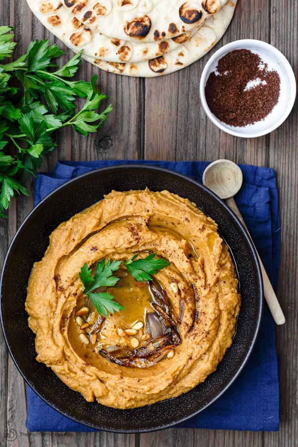 A bowl of rustic Mediterranean Bean Dip with Roasted Acorn Squash and warm pita on the side.