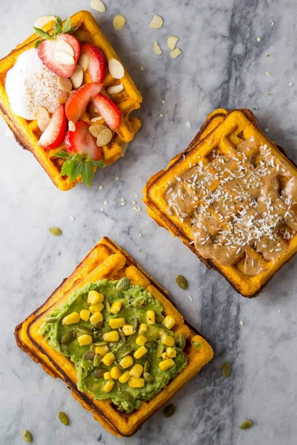 Crispy sweet potato waffles topped with avocado and almond butter for a healthy breakfast.