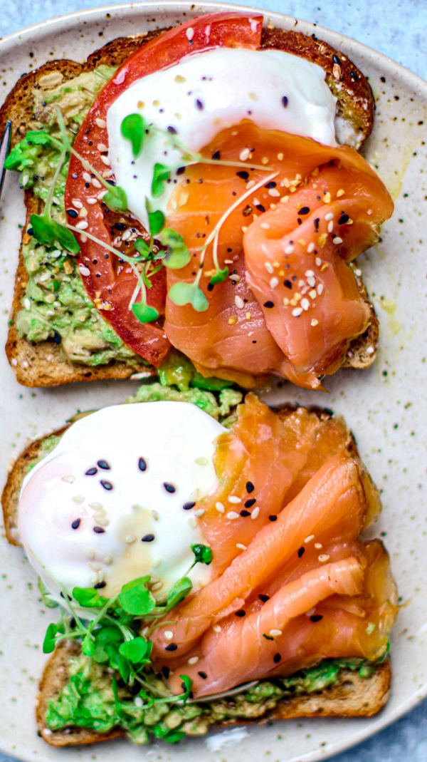 A plate of Smoked Salmon and Poached Eggs on Toast, garnished with microgreens and seasonings.